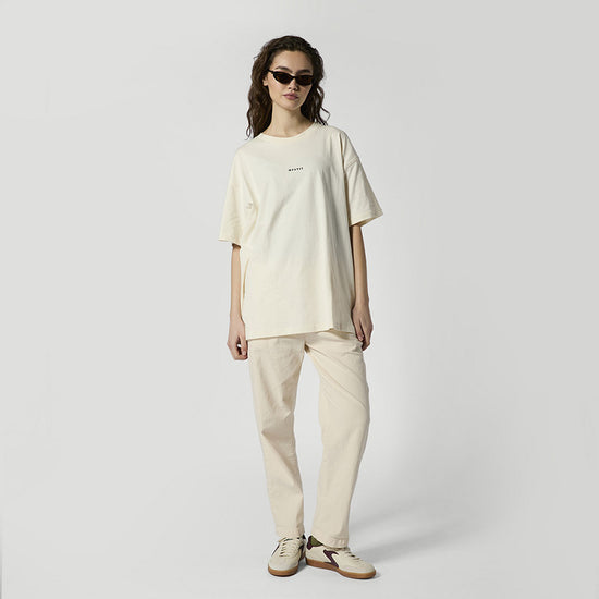 Frau im cremefarbenen boxy T-Shirt mit MYSTIC-Logo und passender Hose