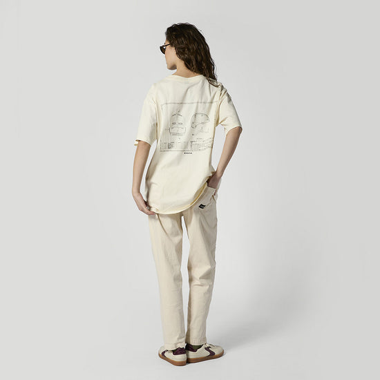 Person im cremefarbenen T-Shirt mit großer Helm-Zeichnung und Sonnenbrille
