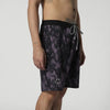 Mystic Boardshorts im Seitenprofil mit schwarz-lila Muster und Smiley-Logo am Beinrand